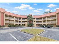 Three-story condo building with red tile roof, white railings, central palm tree island, and parking at 6403 Parc Corniche Dr # 4204, Orlando, FL 32821