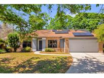 Charming brick home with well-manicured lawn, solar panels, and inviting walkway at 10400 Hunters Trail Ct, Orlando, FL 32817