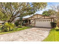 Charming home exterior featuring a well-manicured lawn, mature trees, and a two-car garage at 2508 Osage Trl, Fern Park, FL 32730