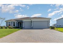 Charming single-story home featuring a brick driveway, neutral paint, manicured lawn, and two-car garage at 4672 Marina Row Dr, Orlando, FL 32820