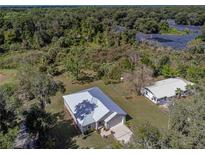 Stunning aerial view of a home with a metal roof surrounded by lush greenery and a manicured lawn at 5694 Aragon Ave, De Leon Springs, FL 32130