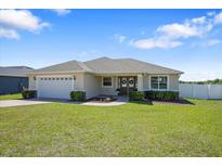 Charming single-story home boasts a lush green lawn, well-manicured landscaping, and an attached two-car garage at 130 Islabella Way, Groveland, FL 34736