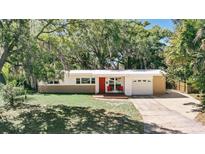 Charming single-story home featuring a well-manicured lawn, a red front door, and mature trees providing shade at 2012 Loch Berry Rd, Winter Park, FL 32792