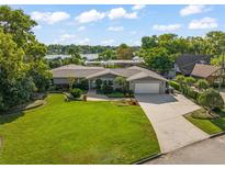 Charming one-story home featuring lush landscaping, a spacious driveway, and a picturesque lake view at 2922 Carmia Dr, Orlando, FL 32806
