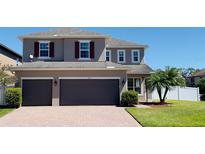 Charming two-story home with a brick driveway, attached two-car garage, manicured lawn, and a small palm tree at 753 Sandy Bar Dr, Winter Garden, FL 34787