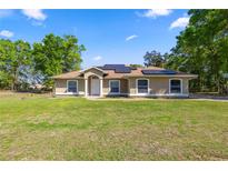 Charming single-story home with lush lawn, solar panels, and well-manicured landscaping at 8499 Se 155Th, Summerfield, FL 34491