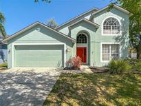 Charming two-story home featuring a red front door, well-maintained lawn, and an attached two-car garage at 101 Sandpebble Pl, Sanford, FL 32771