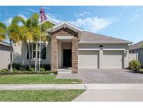 Inviting home featuring a stone facade, well-maintained lawn, and a convenient two-car garage at 1807 Good Neighbor Loop, Kissimmee, FL 34744