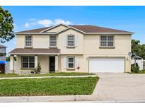 Two-story home with a two-car garage, manicured lawn, and neatly arranged flowerbeds beneath front windows at 1928 Crestridge Dr, Clermont, FL 34711
