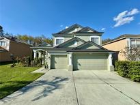 Inviting two-story home with a manicured lawn, three-car garage, and classic architectural details under a bright blue sky at 2014 Applegate Dr, Ocoee, FL 34761