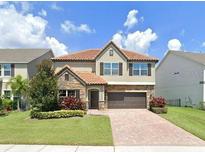 Charming two-story home with a red tile roof, brick accents and manicured landscaping at 528 Egret Place Dr, Winter Garden, FL 34787
