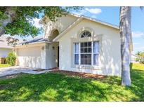 Charming home exterior featuring a well-maintained lawn, two-car garage, and large window at 7911 Magnolia Bend Ct, Kissimmee, FL 34747