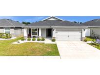 Inviting home featuring a two-car garage, landscaped front yard, and a cozy porch with seating at 8043 Brookeshire Dr, Lakeland, FL 33809