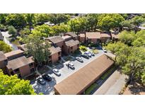 Aerial view showcases the community's brown buildings, lush trees, parking, and serene pond at 1092 E Michigan St # 1, Orlando, FL 32806