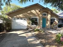 Inviting home exterior featuring a bright blue door, lush landscaping, and a convenient one car garage at 1115 Naples Dr, Orlando, FL 32804