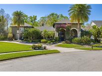 Beautiful exterior of home with lush landscaping, palm trees, and a charming brick walkway at 115 Ellington Pl, Oviedo, FL 32765
