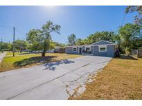 Charming single-story home with a spacious front yard and a long concrete driveway under a bright blue sky at 5206 Cortez Dr, Orlando, FL 32808