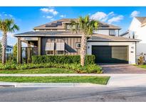 Beautiful two-story home featuring a dark gray two-car garage, solar panels, and manicured landscaping at 6439 Trailblaze Bnd, St Cloud, FL 34771