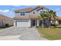 Beautiful two-story home featuring a well-manicured lawn, neutral color palette, and a paved driveway leading to a two-car garage at 1158 Oak Bluff Dr, Davenport, FL 33837