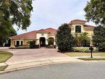 Stunning yellow single-story home with red tile roof, lush landscaping, and a circular driveway at 11954 Provincial Way, Windermere, FL 34786