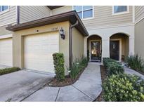 Inviting townhome featuring a one-car garage, manicured landscaping, and covered entryway at 1284 Pavia Dr, Apopka, FL 32703