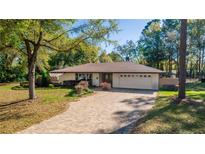 Charming single-story home with a brick driveway, attached garage, and manicured landscaping at 135 Hilltop Pl, Altamonte Springs, FL 32701