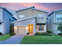 Charming two-story home with a stone facade, well-manicured lawn, and a brick driveway leading to an attached garage at 2805 Bookmark Dr, Kissimmee, FL 34746