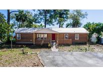 Charming single-story home with a red door, metal roof and a wooden deck at 36112 Lake Unity Rd, Fruitland Park, FL 34731