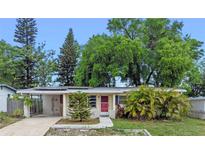 Charming single-story home with a well-manicured lawn, mature trees, and a welcoming red front door at 6031 W Ridgewood Ave, Orlando, FL 32835