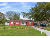 Cozy one-story home featuring a bright red facade, well-maintained lawn, and mature trees offering shade at 2817 Sprague Dr, Orlando, FL 32826