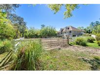 Exterior view of house and paddock with lush greenery, white fencing and a metal gate at 3149 Scrub Oak Trl, Oviedo, FL 32765