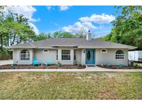 Charming single-story home with a blue door, landscaped front yard, and inviting curb appeal at 34731 Estes Rd, Eustis, FL 32736