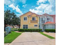 A townhome featuring a red tile roof, black iron balcony, yellow exterior, and a well-kept lawn at 4720 Hemingway House St, Kissimmee, FL 34746