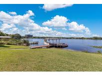 Expansive lake view featuring a dock with a covered sitting area and lush green landscaping at 673 Balmoral Rd, Winter Park, FL 32789