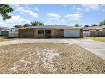 Charming single-story home featuring a stone facade, solar panels, a two-car garage and a curved driveway at 690 S Lakemont Ave, Winter Park, FL 32792