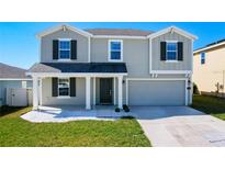 Charming two-story home featuring a landscaped front yard, attached garage, and welcoming covered front porch at 744 Simone Ct, Haines City, FL 33844
