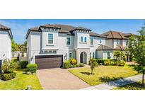 Beautiful two-story home with a well-manicured lawn, brick driveway, and gray stucco exterior at 8384 Ludington Cir, Orlando, FL 32836