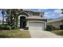 Charming two-story home featuring an attached two car garage and well maintained landscaping with palm trees at 8500 Palm Harbour Dr, Kissimmee, FL 34747
