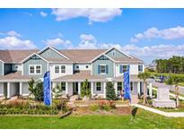 A beautiful two-story townhouse with blue accents, a covered porch, and professionally landscaped grounds at 13532 Autumn Harvest Ave, Winter Garden, FL 34787