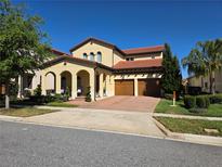 Beautiful two-story home featuring a red tile roof, arched entryway, a three-car garage, and manicured landscaping at 15149 Canoe Pl, Winter Garden, FL 34787