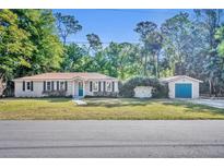 Charming single-story home with a detached garage and well-maintained lawn and mature landscaping at 225 N Phippen Ave, Deland, FL 32724