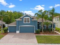 Charming two-story home featuring a three-car garage, lush landscaping, and a brick driveway at 820 Timber Isle Dr, Orlando, FL 32828
