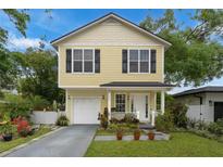 Charming two-story home with yellow siding, black shutters, manicured lawn and a one car garage at 1027 Altaloma Ave, Orlando, FL 32803