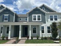 Charming townhome showcasing a beautifully landscaped yard, columned porch, and stylish two-tone exterior at 13536 Autumn Harvest Ave, Winter Garden, FL 34787