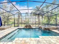Relaxing screened pool area with a waterfall feature, stone accents, and lush tropical landscaping at 1813 Vista Meadows Dr, Ocoee, FL 34761