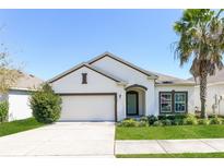 Charming single-story home with a manicured lawn and a white exterior complemented by a neatly trimmed palm tree at 2430 Sanderling St, Haines City, FL 33844