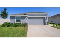Charming single-story home with a gray exterior, a two-car garage, and a well-manicured lawn at 660 Silver Palm Dr, Haines City, FL 33844