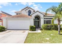Charming two-story home featuring a manicured lawn, attached two-car garage, and inviting front entrance at 745 Riggs Cir, Davenport, FL 33897