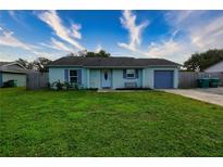 Charming single-story home featuring light blue siding, an attached garage and a well-maintained lawn at 1491 Lavender St, Deltona, FL 32725