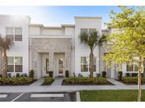 Modern townhome showcasing a sleek facade, decorative stone accents, and lush landscaping with tropical palm trees at 17228 Blessing Dr, Clermont, FL 34714